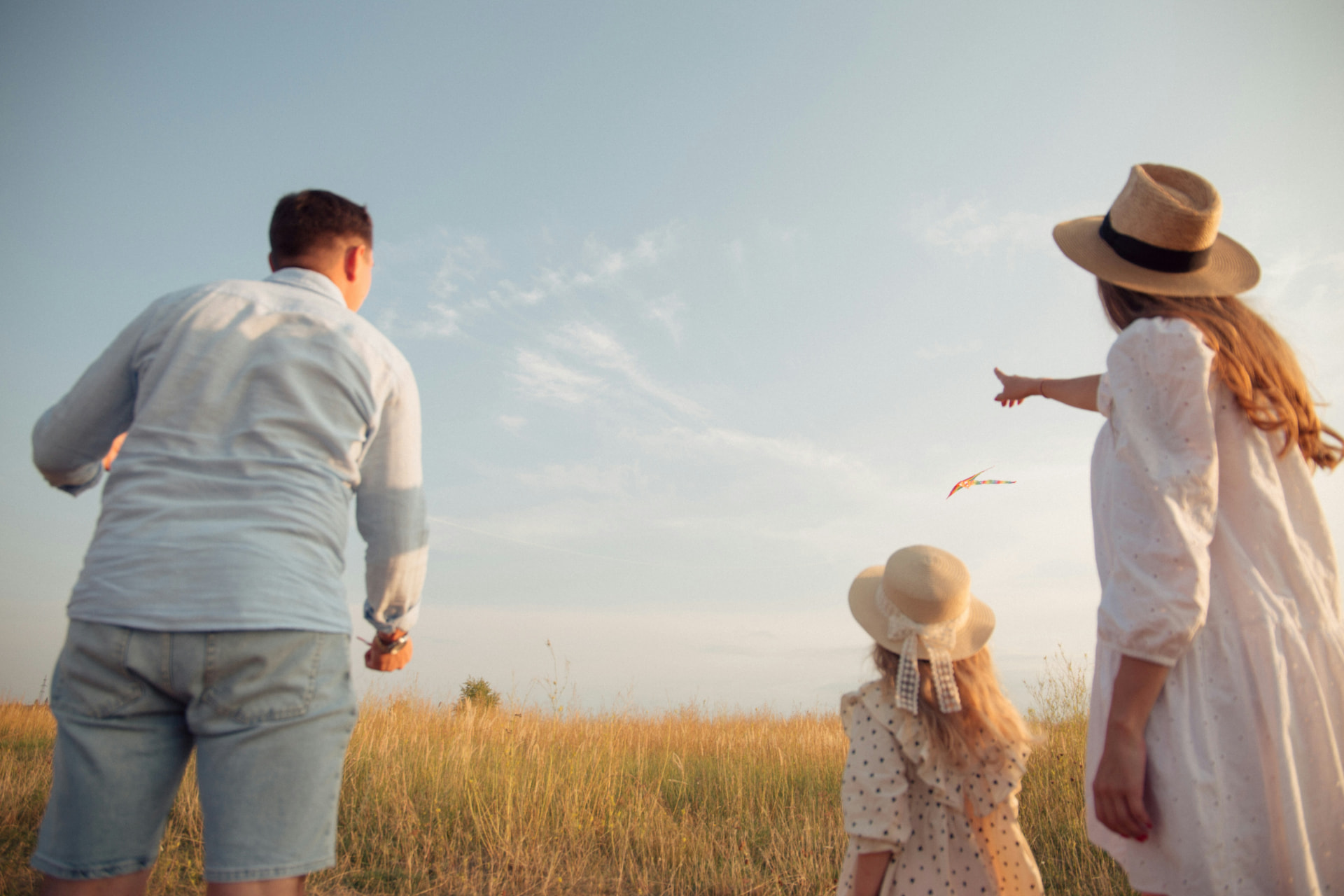 A family flying a kite together in a golden Orange County meadow at sunset
